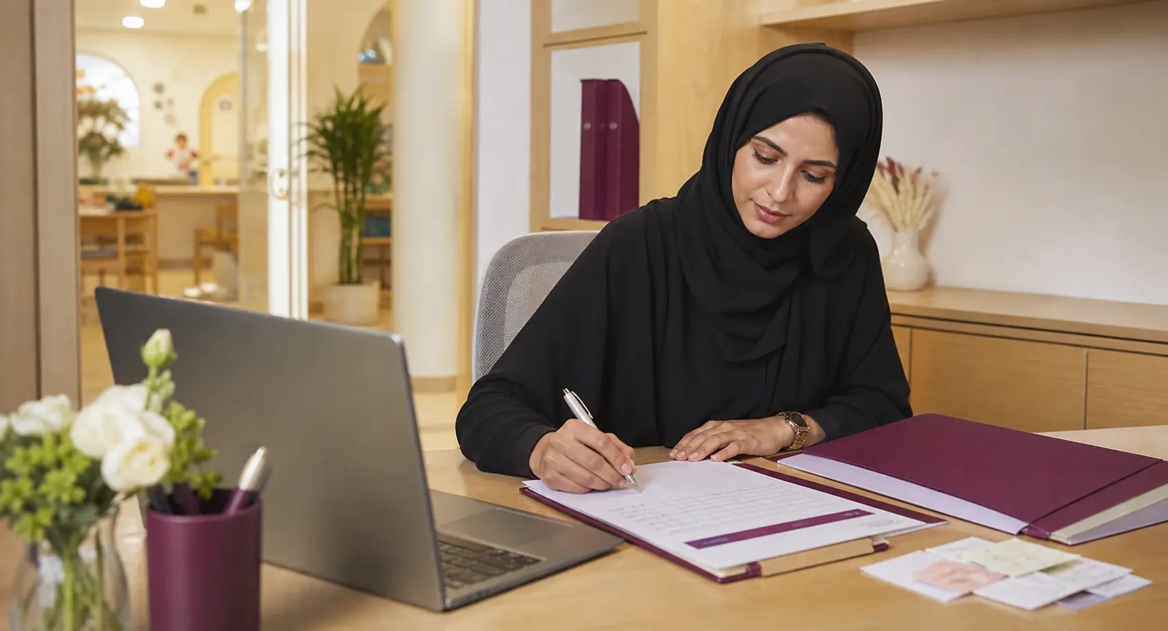 Nursery finance administrator reviewing payment records on a laptop in a calm office