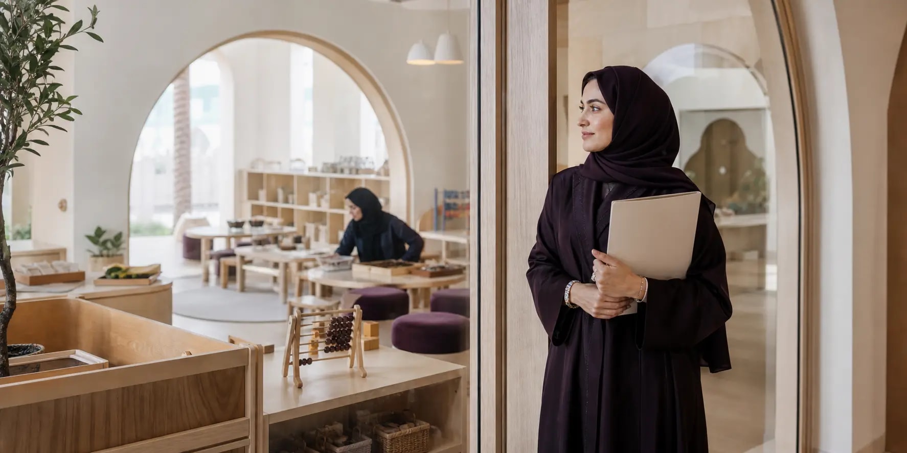 Nursery director observing a calm classroom through a glass partition